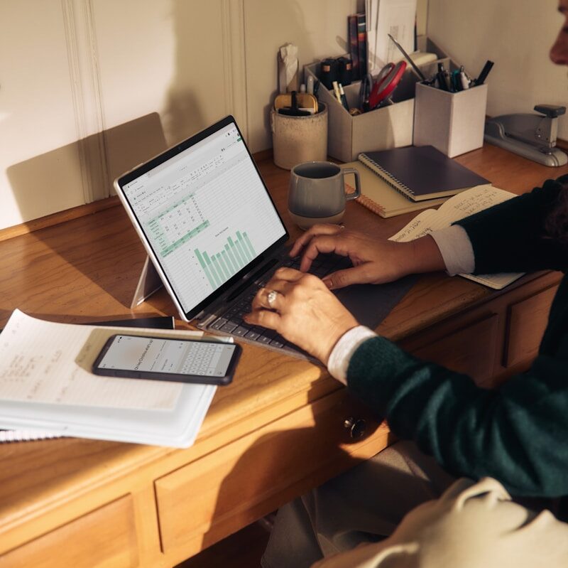 Person working on laptop at a wooden desk.